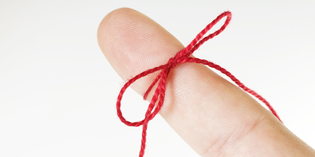 Red ribbon tied around finger